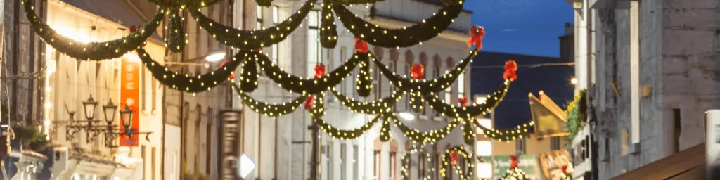 Christmas lights and festive decorations hanging over a street in Galway, Ireland, during the holiday season. | The Dawson Hostel