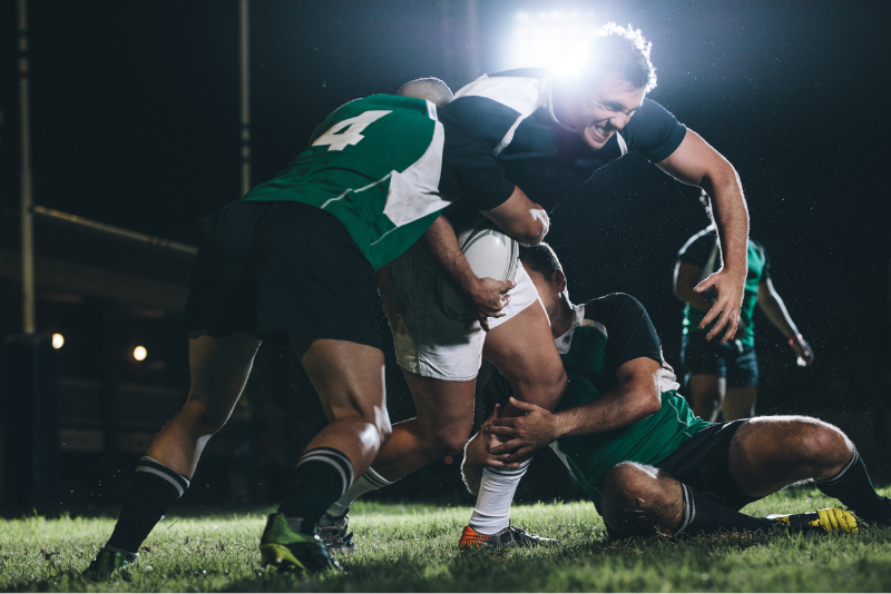 Connacht rugby players tackling an opponent during a match, with budget accommodation for rugby fans at The Dawson Hostel Galway.