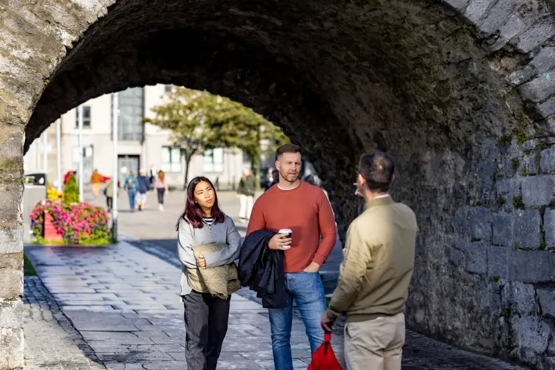 Visitors walking under the Spanish Arch in Galway, near The Dawson Hostel offering affordable accommodation near Spanish Arch Galway